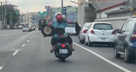 機車雙載危險上路　　後座乘客抱著巨型時鐘鏡險象環生