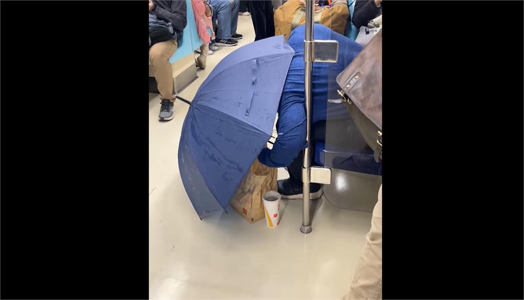 快新聞／有那麼餓？男子在北捷車廂撐傘彎腰吃麥當勞　誇張行徑全曝光