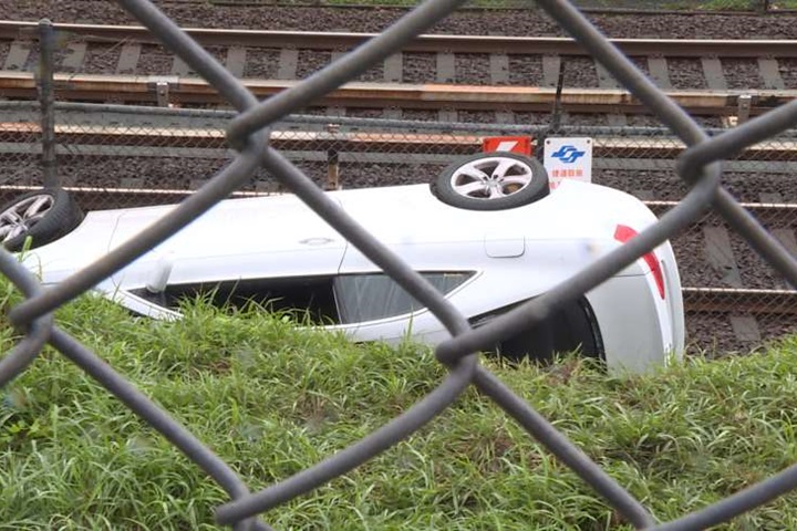 驚險！轎車翻覆卡圍籬 險落通電捷運軌道